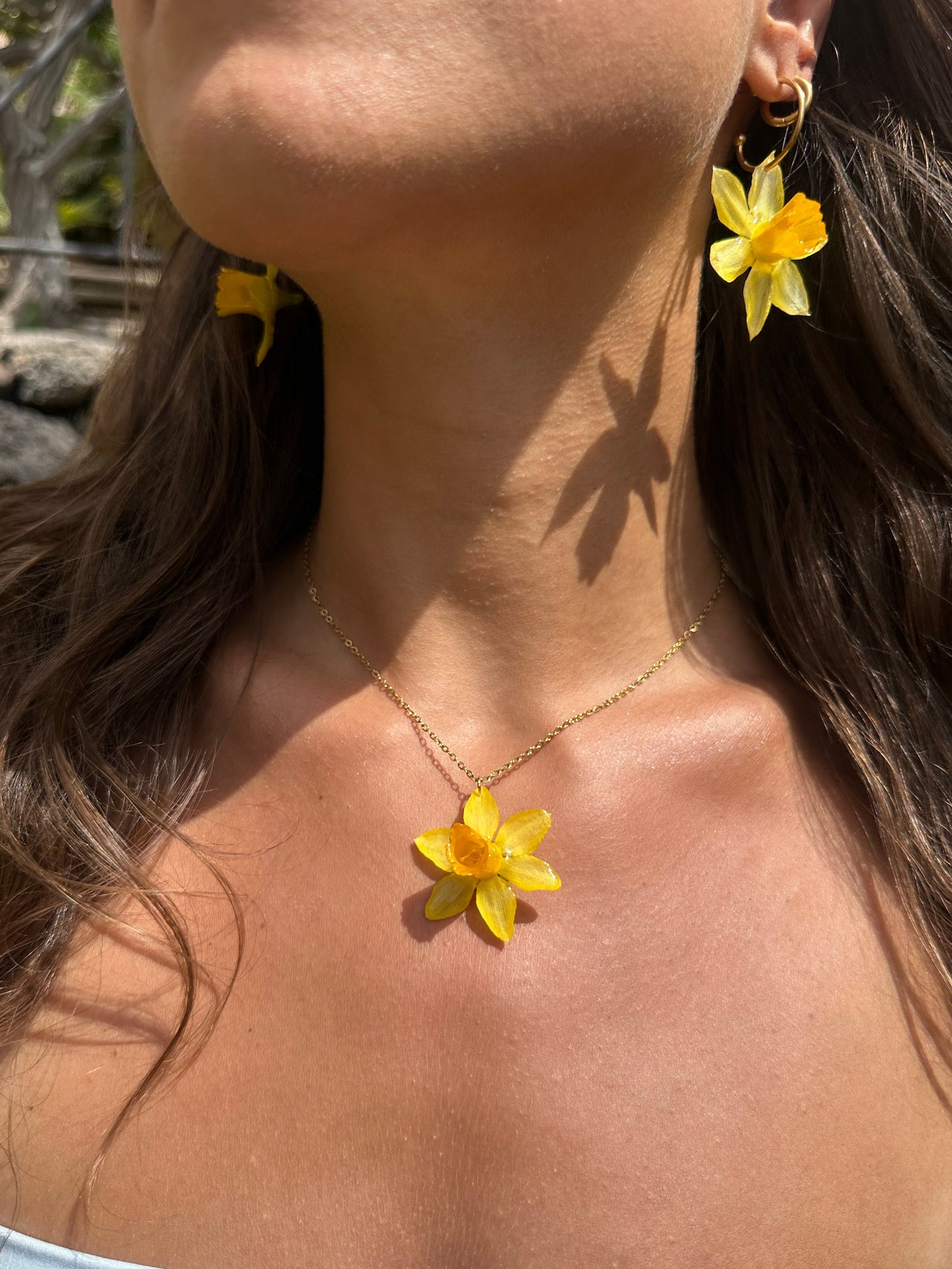 Person wearing yellow daffodil necklace and earrings